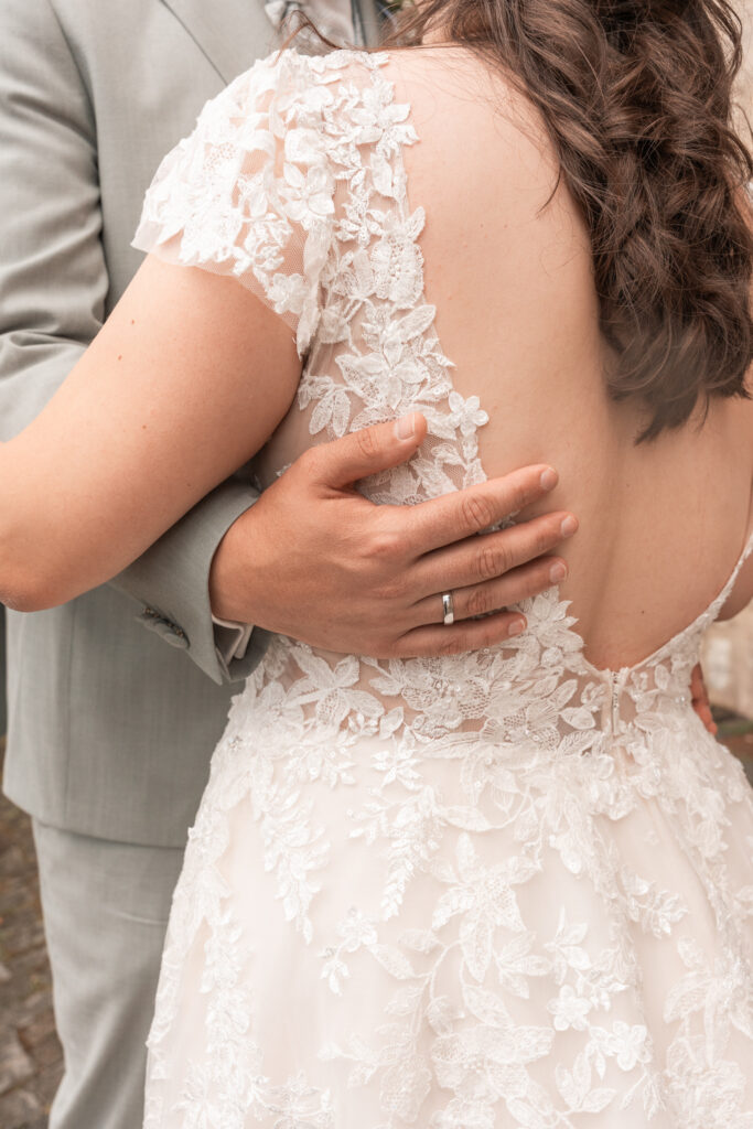Hand des Bräutigams liegt auf dem Rücken der Braut